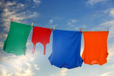 Different clothes drying on washing line against blue sky