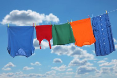 Different clothes drying on washing line against blue sky