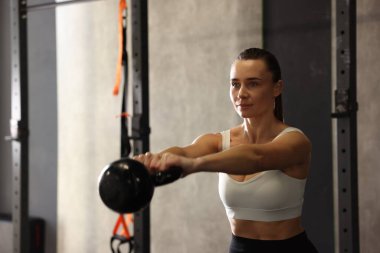 Sporcu kadın jimnastik yaparken kettlebell salıncak yapıyor. Metin için boşluk