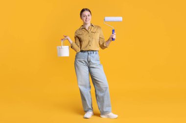 Turuncu arka planda bir kova boyası olan bir kadın.