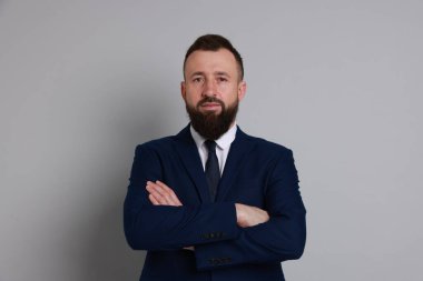 Gri arka planda takım elbiseli yakışıklı sakallı adam.