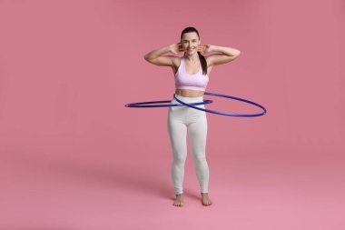 Gülümseyen kadın eğitimi pembe arka planda hula hooplarla