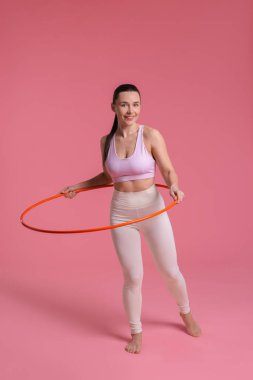 Gülümseyen kadın eğitimi pembe arka planda hula hoop ile