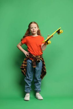 Yeşil arka planda bozuk para tahtasıyla şık küçük kız.