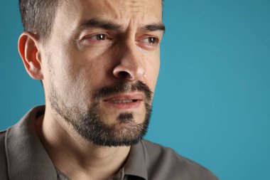 Üzgün adam açık mavi arka planda ağlıyor, yakın plan