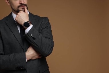 Kahverengi arka planda klasik takım elbiseli adam, yakın plan. Metin için boşluk