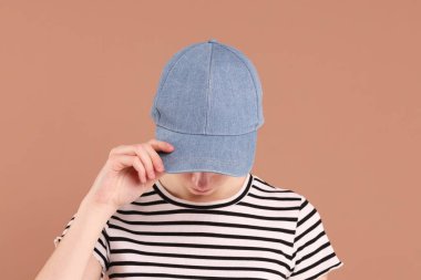 Beyzbol şapkalı, bej arka planda bir kadın. Tasarım için model