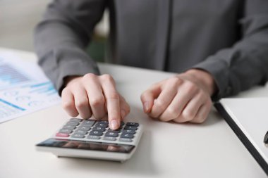 Bütçe. Evrak işleri ve hesap makinesi olan bir kadın beyaz masa içinde, yakın plan.