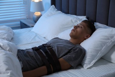 Uyurgezer yatağa uzanmış kemerlerle bağlı