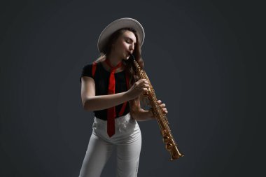 Gri arkaplanda soprano saksafon çalan müzisyen