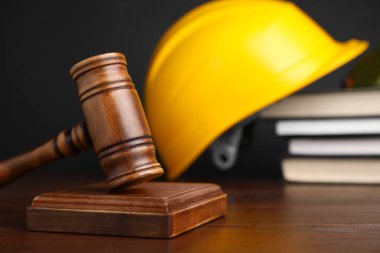 İş yerinde kaza oldu. Gavel, kitaplar ve inşaat işçilerinin koruyucu giysileri ahşap masada, seçici odaklı.