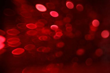 Kırmızı arkaplandaki neşeli ışıkların bulanık görüntüsü. Bokeh etkisi
