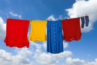 Different clothes drying on washing line against blue sky