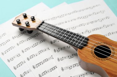Turkuaz arka planda Ukulele ve müzik sayfaları, yakın plan