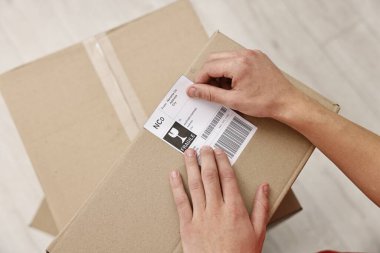 Paketin içine barkodlu nakliye etiketi yapıştıran bir adam var.