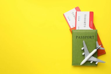 Seyahat acentesi. Uçuş biletleri, pasaportlar ve sarı arka planda uçak modeli. Metin için boşluk