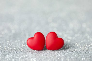 Parlak gümüş arka planda kırmızı dekoratif kalpler. Sevgililer günün kutlu olsun.