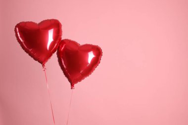 Pembe arka planda iki kırmızı kalp şeklinde balon, mesaj için boşluk. Sevgililer Günün kutlu olsun.
