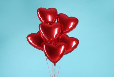 Açık mavi arka planda bir sürü kırmızı kalp şeklinde balon. Sevgililer Günün kutlu olsun.