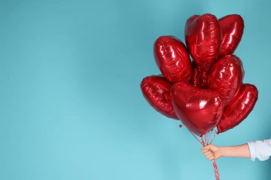 Sevgililer Günün kutlu olsun. Açık mavi arka planda kırmızı kalp şeklinde balonları olan adam, yakın plan. Metin için boşluk
