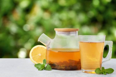 Aromatik nane çayı, taze yapraklar ve açık gri masada limon. Metin için boşluk