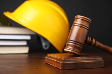 İş yerinde kaza oldu. Gavel, kitaplar ve inşaat işçilerinin koruyucu giysileri ahşap masada, seçici odaklı.