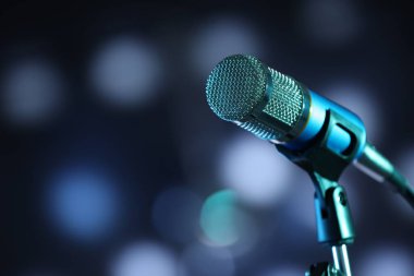 Karanlık arka planda duran bulanık ışıklı mikrofon, mesaj için yer var. Bokeh etkisi