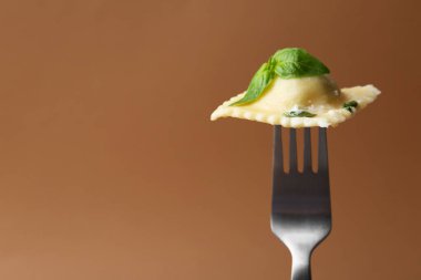 Peynirli ve fesleğenli lezzetli ravioli kahverengi arka planda, yakın plan. Metin için boşluk