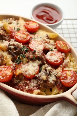 Peynirli, domatesli, kıymalı ve kekikli makarna güveci beyaz masada, yakın plan.