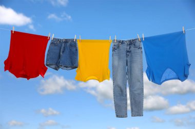 Different clothes drying on washing line against blue sky