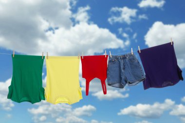 Different clothes drying on washing line against blue sky