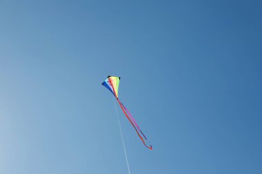 Mavi gökyüzünde uçan renkli bir uçurtma
