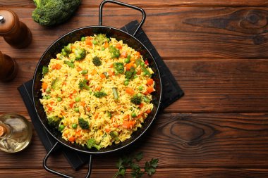 Sebzeli lezzetli pirinç, ahşap masada servis edilir, üst manzara. Metin için boşluk