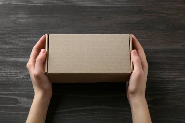 Karanlık ahşap arka planda boş karton kutulu bir kadın, yakın plan. Tasarım için model