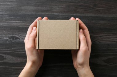 Koyu ahşap arka planda, boş karton kutulu kadın, üst manzara. Tasarım için model
