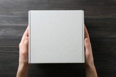 Koyu ahşap arka planda, boş karton kutulu kadın, üst manzara. Tasarım için model