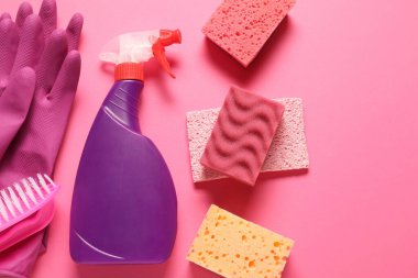 Pembe arka planda sprey temizleme ürünü ve araçları düz yatıyordu