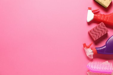 Pembe arka planda temizlik ürünleri ve aletler, düz yatak. Metin için boşluk