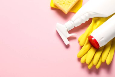 Pembe arka planda bir şişe temizlik malzemesi ve aletler, düz konum. Metin için boşluk