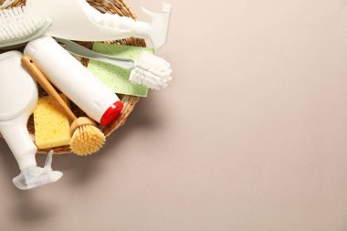 Bej arka planda farklı temizlik ürünleri ve aletleri, üst görünüm. Metin için boşluk