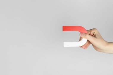 Gri arka planda at nalı mıknatısı olan kadın, yakın plan. Metin için boşluk