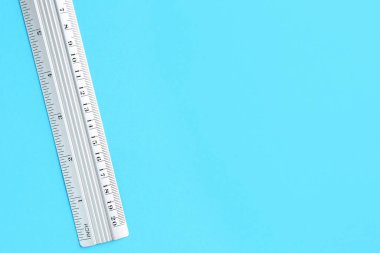 Açık mavi arka planda bir metal cetvel, üst manzara. Metin için boşluk