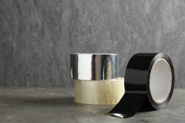 Gri masadaki farklı yapıştırıcı bantların ruloları, metin için boşluk