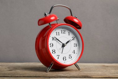 Gri arkaplana karşı ahşap masada bir kırmızı alarm saati