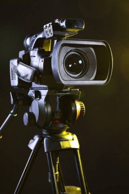 Siyah arka planda tripodu olan modern video kamera, yakın plan