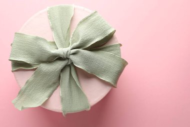 Pembe arka planda güzel bir fiyonklu hediye kutusu, üst manzara. Metin için boşluk