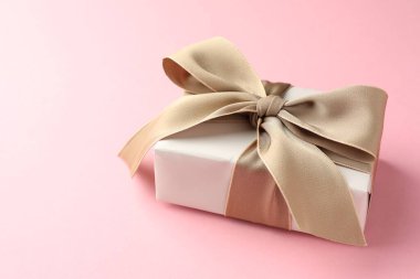Pembe arka planda güzel fiyonklu hediye kutusu. Metin için boşluk