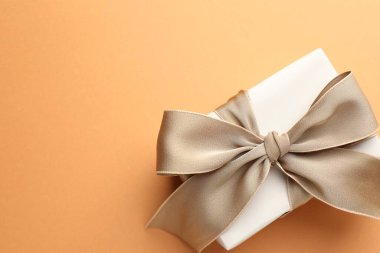 Mercan arka planında güzel bir fiyonk olan hediye kutusu, üst manzara. Metin için boşluk