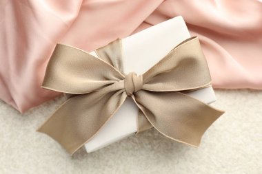 Işık arkaplanda güzel bir fiyonk ve kumaş olan hediye kutusu, üst manzara.