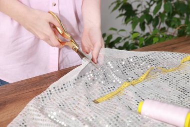 Atölyede kumaşı pullarla kesen kadın, yakın plan.